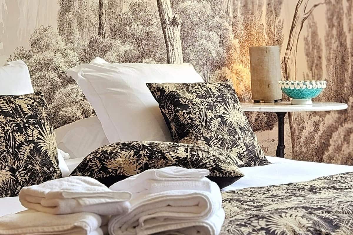 Une chambre à coucher avec un lit, des oreillers, une lampe suspendue et une fresque murale.