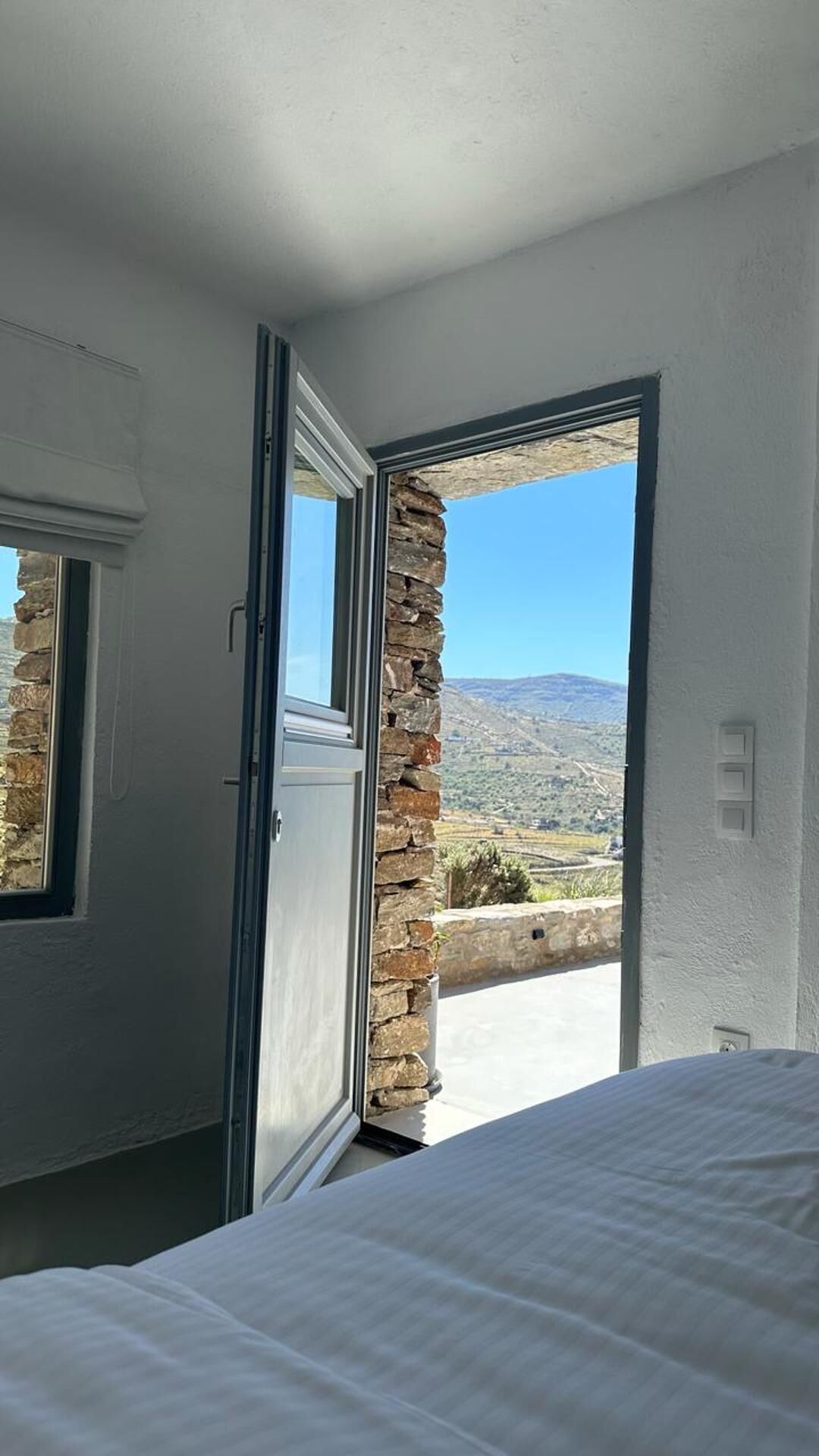 A bedroom with a bed, a window, and a view of a mountainous landscape.