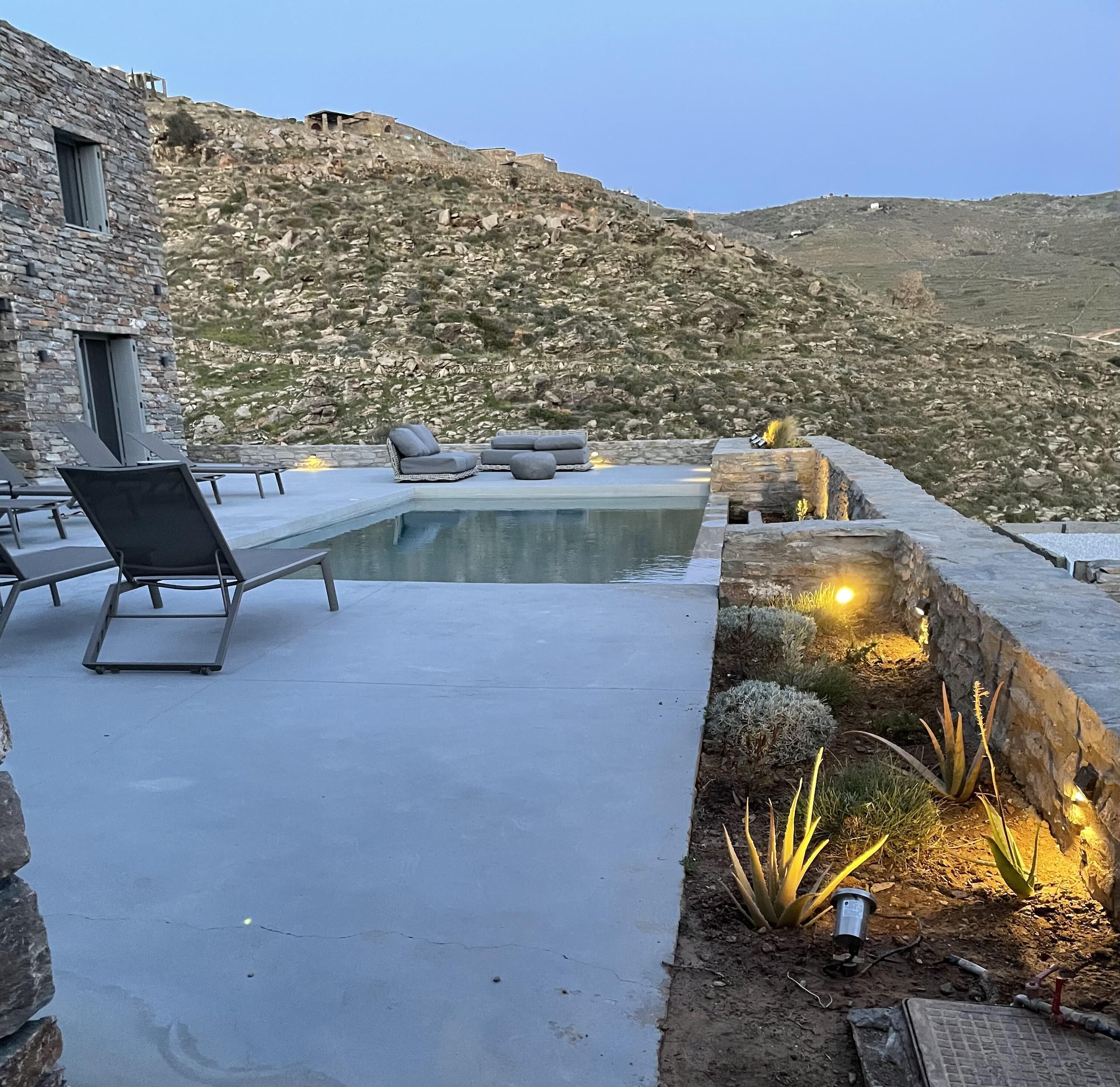 A pool area with lounge chairs and a stone building in the background.