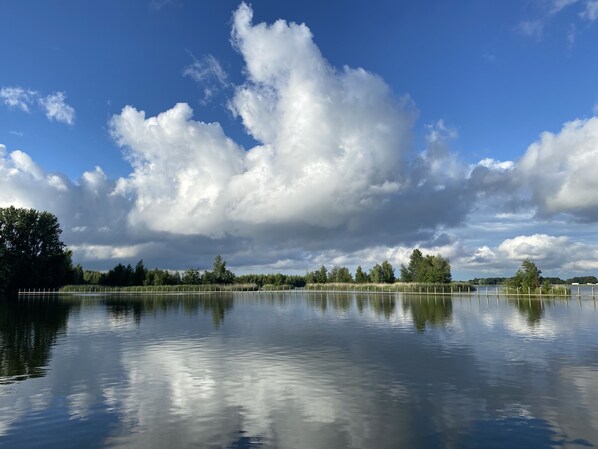A calm lake with a wooden dock and trees in the background.