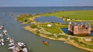 Un château entouré d’eau, de bateaux et de champs verdoyants.