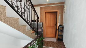 A staircase with a wrought iron railing, a wooden door at the top, and a patterned rug on the floor. - Vila Domm in Rakovica (Rakovica)
