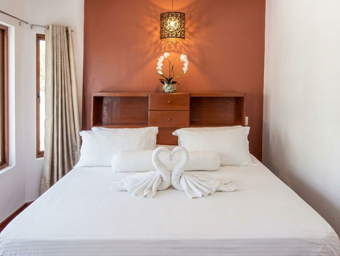 Une chambre d’hôtel avec un lit, une table de chevet, une lampe et une fenêtre avec des rideaux.