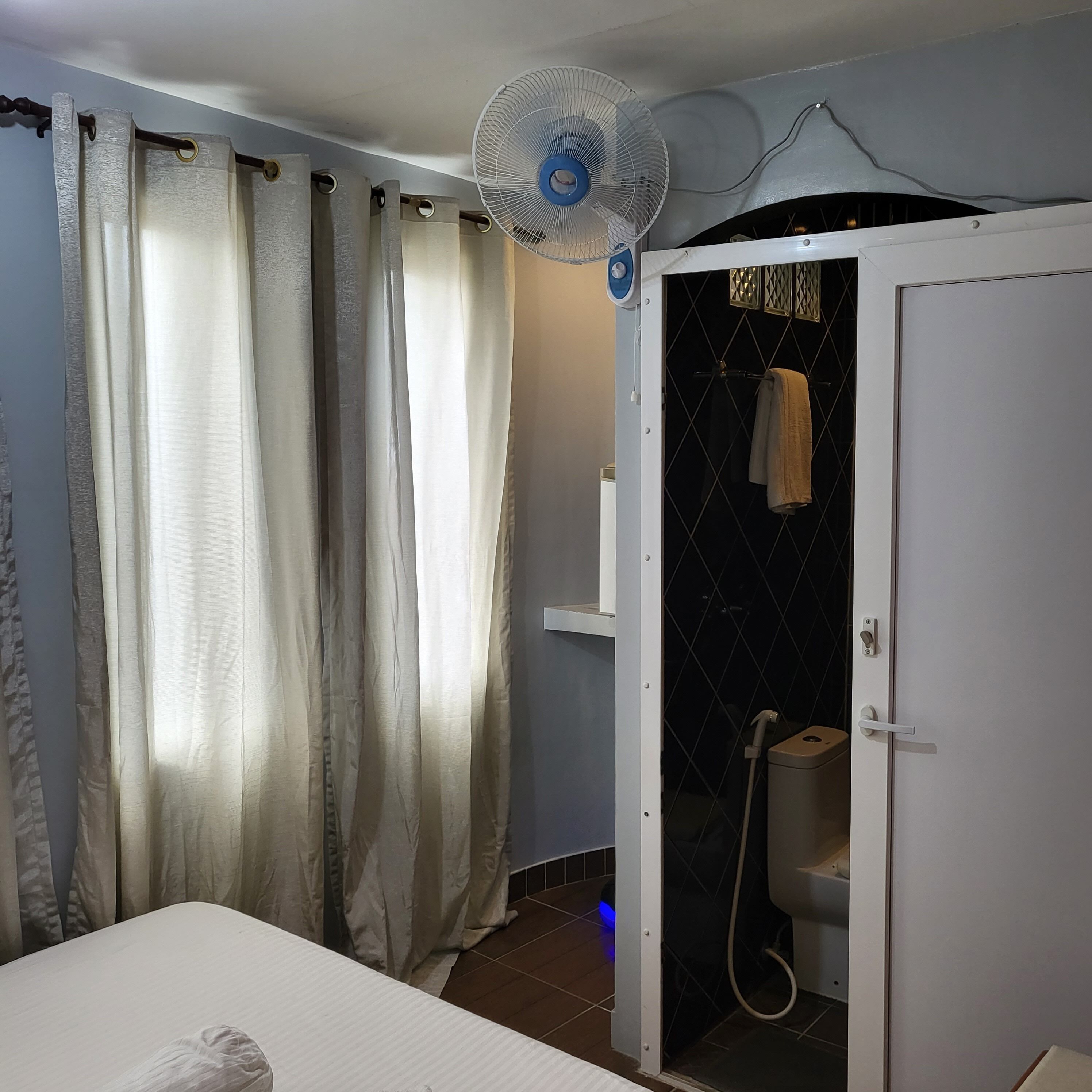 Ein Badezimmer mit Dusche, Toilette und einem Bett mit weißer Matratze.