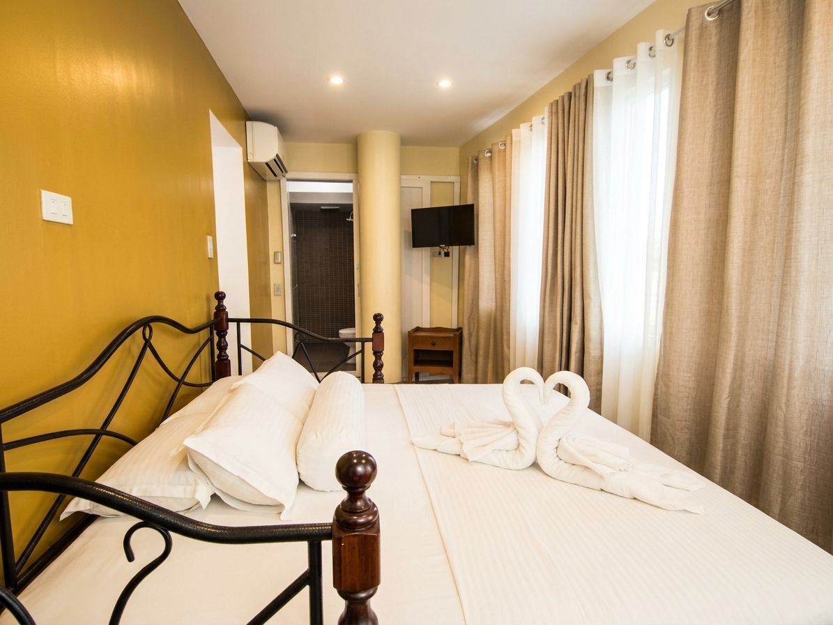A hotel room with a bed, a television, and curtains.