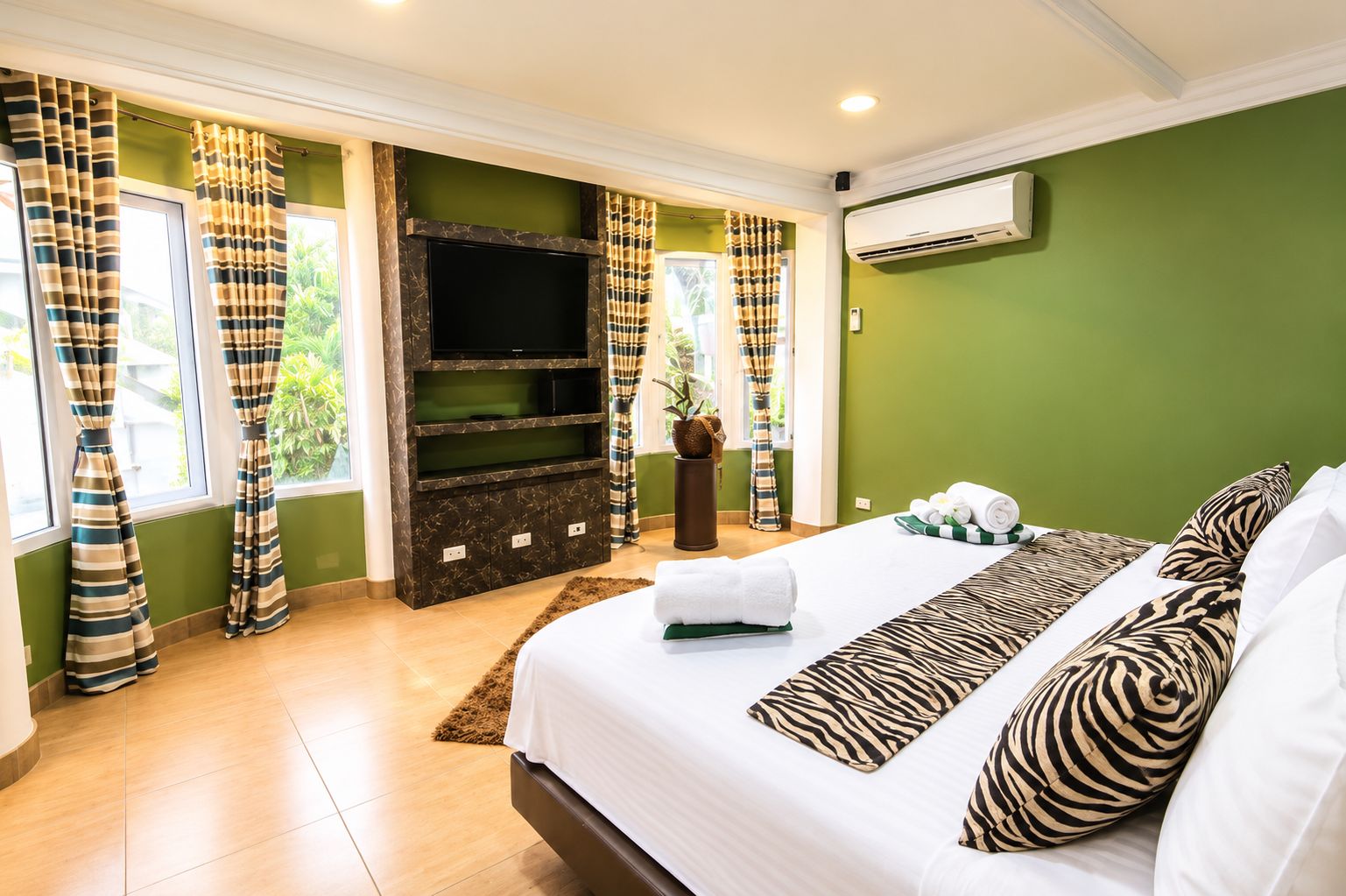 Une chambre d’hôtel avec un lit, un téléviseur à écran plat, une plante en pot et une vue sur la verdure environnante.
