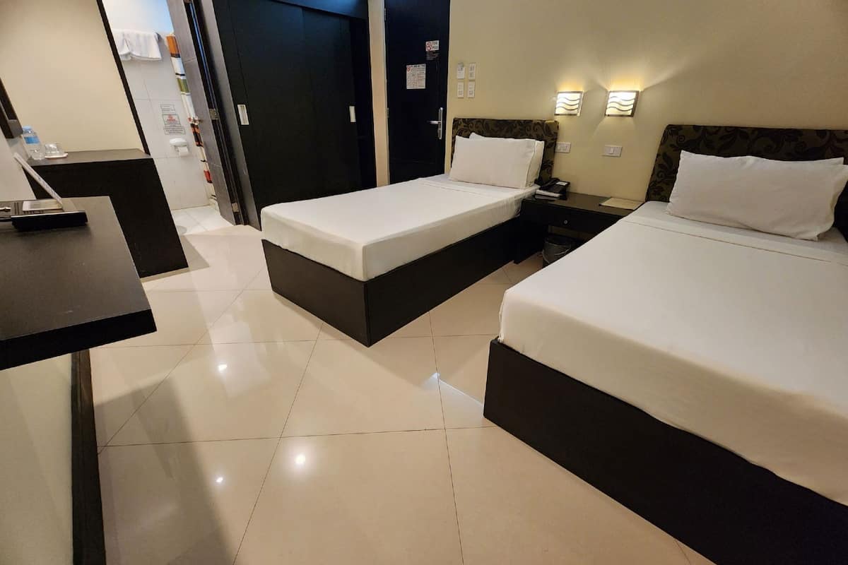 A hotel room with two beds, a desk, and a bathroom visible through an open door.