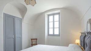 Ein Schlafzimmer mit einem Bett, einem Fenster, einem Stuhl und einer Lampe.