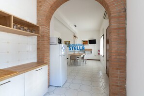 A kitchen with a wooden countertop, white cabinets, a refrigerator, and a brick archway. - * Giglio * / Piazza Marconi [park] (Lido di Jesolo)