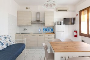 A modern kitchen with a dining area, a bed, and a fire extinguisher.