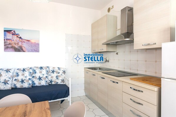 A compact kitchen with a wooden countertop, a built-in stove, and a stainless steel range hood.