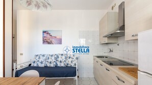 Eine kleine Küche mit Bett, Essbereich und Blick auf einen Strand.