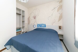 Une chambre Ă coucher comprenant un lit, une armoire et un mur ornĂ© dâun motif floral.
