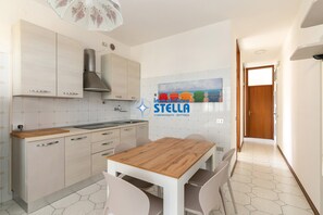 A modern kitchen with a wooden table and chairs, a built-in stove, and a tiled backsplash.