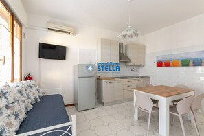 A compact living space with a kitchenette, a dining area, and a bed with floral bedding.