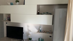 Una cucina moderna con frigorifero integrato, televisore e piano di lavoro in legno.