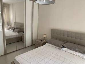 A bedroom with a bed, a nightstand, a mirror, and a lamp. - Relax right by the sea in Silvi Marina.<br>Jun 25–Jul 30–Aug 20 (Silvi Marina)