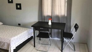A bedroom with a bed, a desk with a chair, and a window with curtains. - Relaxing Beachfront Apartment steps to the beach (las pascualas)