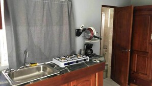 A compact kitchen with a gas stove, sink, and wooden cabinets. - Relaxing Beachfront Apartment steps to the beach (las pascualas)