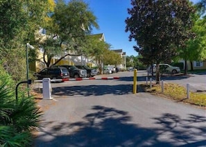Ein durch einen Zaun gesichertes Parkgebiet mit Fahrzeugen, Bäumen und Gebäuden im Hintergrund.