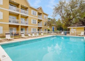 A hotel with a swimming pool, multiple balconies, and a fenced area with lounge chairs. - 2 Adult Bikes! Walk to Pool & Beach! Heart of Seagrove - Summer Breeze at Seagrove Beach 30A (Santa Rosa Beach)
