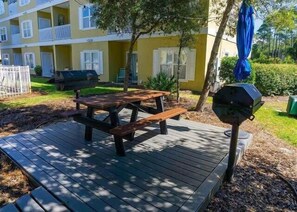 Eine Holzterrasse mit Picknicktisch und Grill.