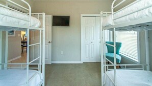 Een kamer met stapelbedden, een televisie aan de muur en een deur naar een andere kamer.