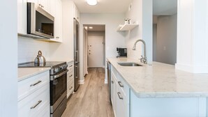 A modern kitchen with white cabinetry, stainless steel appliances, and a marble countertop. - Prime Eastport Location - Waterfront Condo w Pool & Parking (Annapolis)