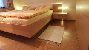 Een moderne slaapkamer met een bed, nachtkastjes en een nachttafeltje.
