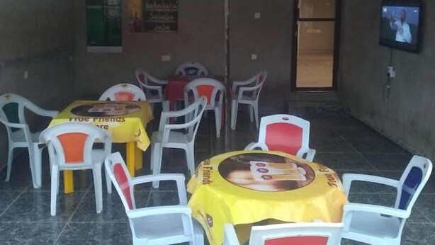 Un espacio de estar al aire libre cubierto con sillas y mesas de plástico, algunas con manteles amarillos.