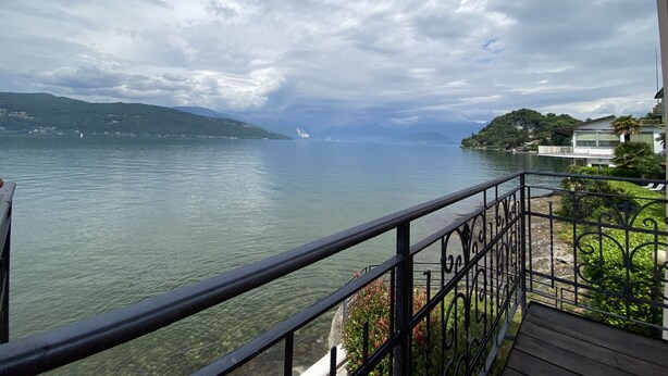 A balcony with a view of a lake and distant mountains. - Vacation apartment directly on the lake (Leggiuno)
