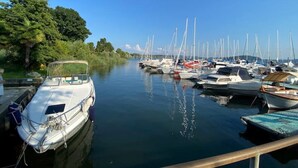 Een jachthaven met diverse boten afgemeerd langs een rustig water, omgeven door weelderige begroeiing.