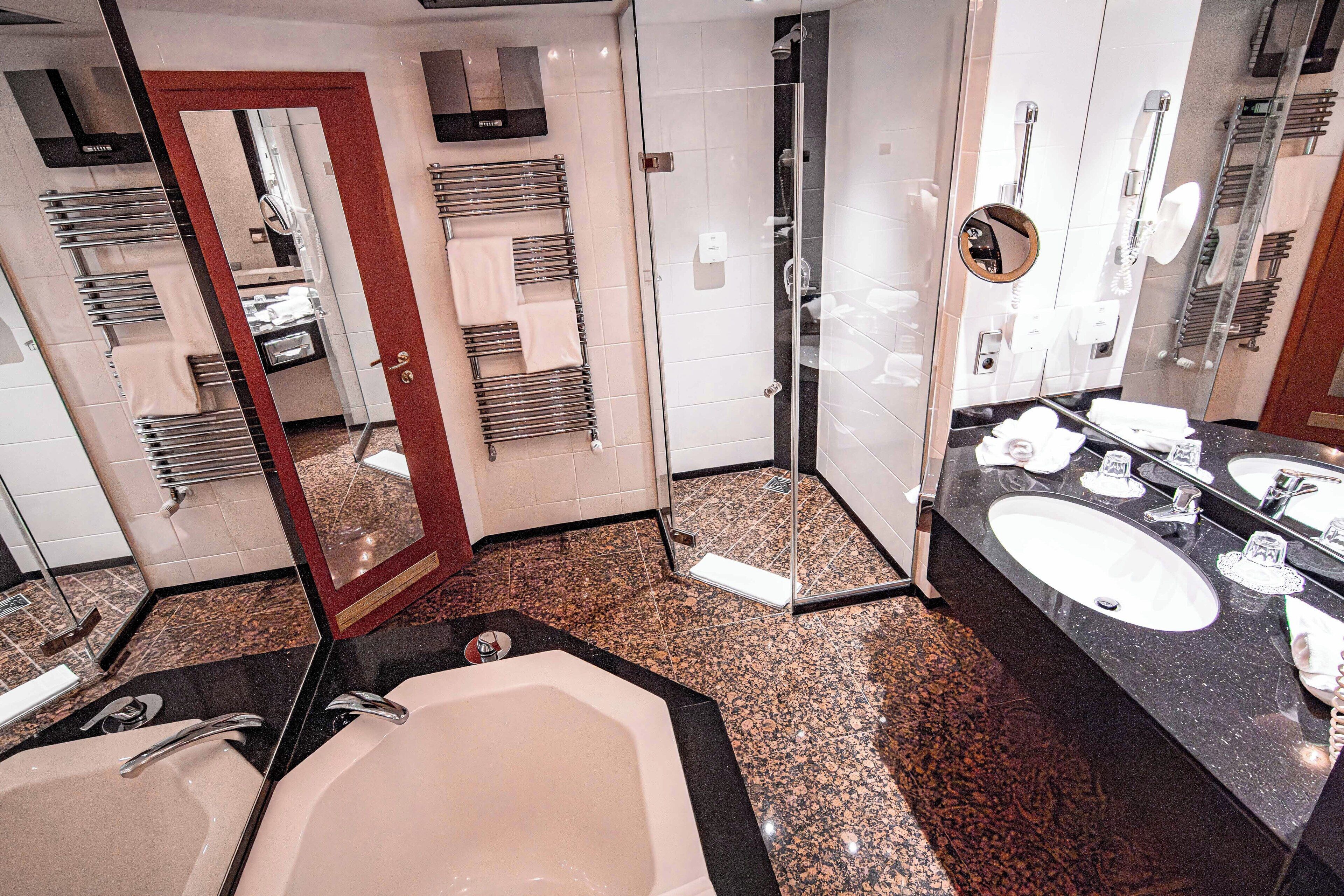 Un baño moderno con una bañera grande, dos lavamanos, cabina de ducha de vidrio y un espejo con marco redondo.