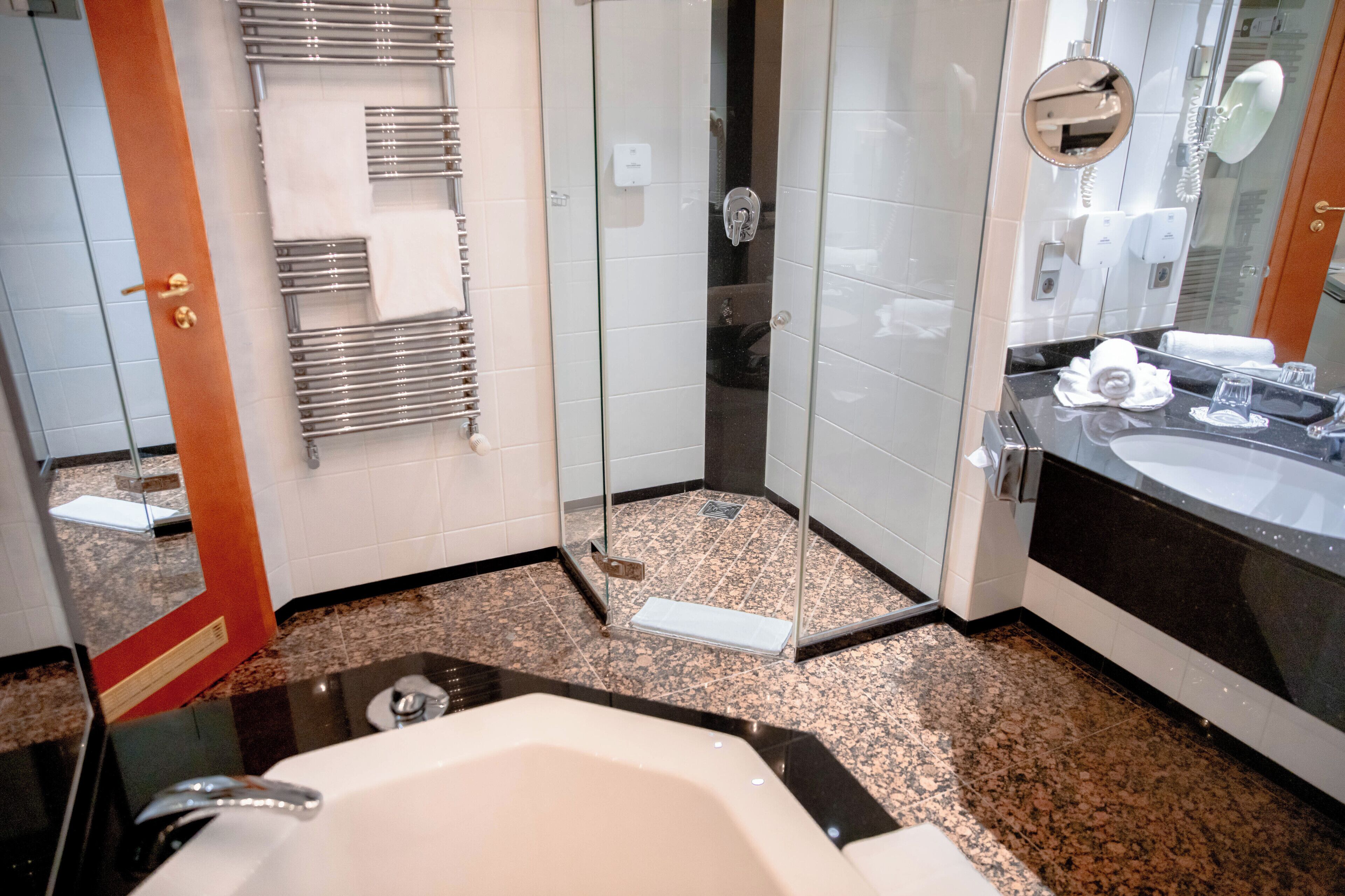 Un baño moderno con ducha de vidrio, bañera y tocador con espejo.