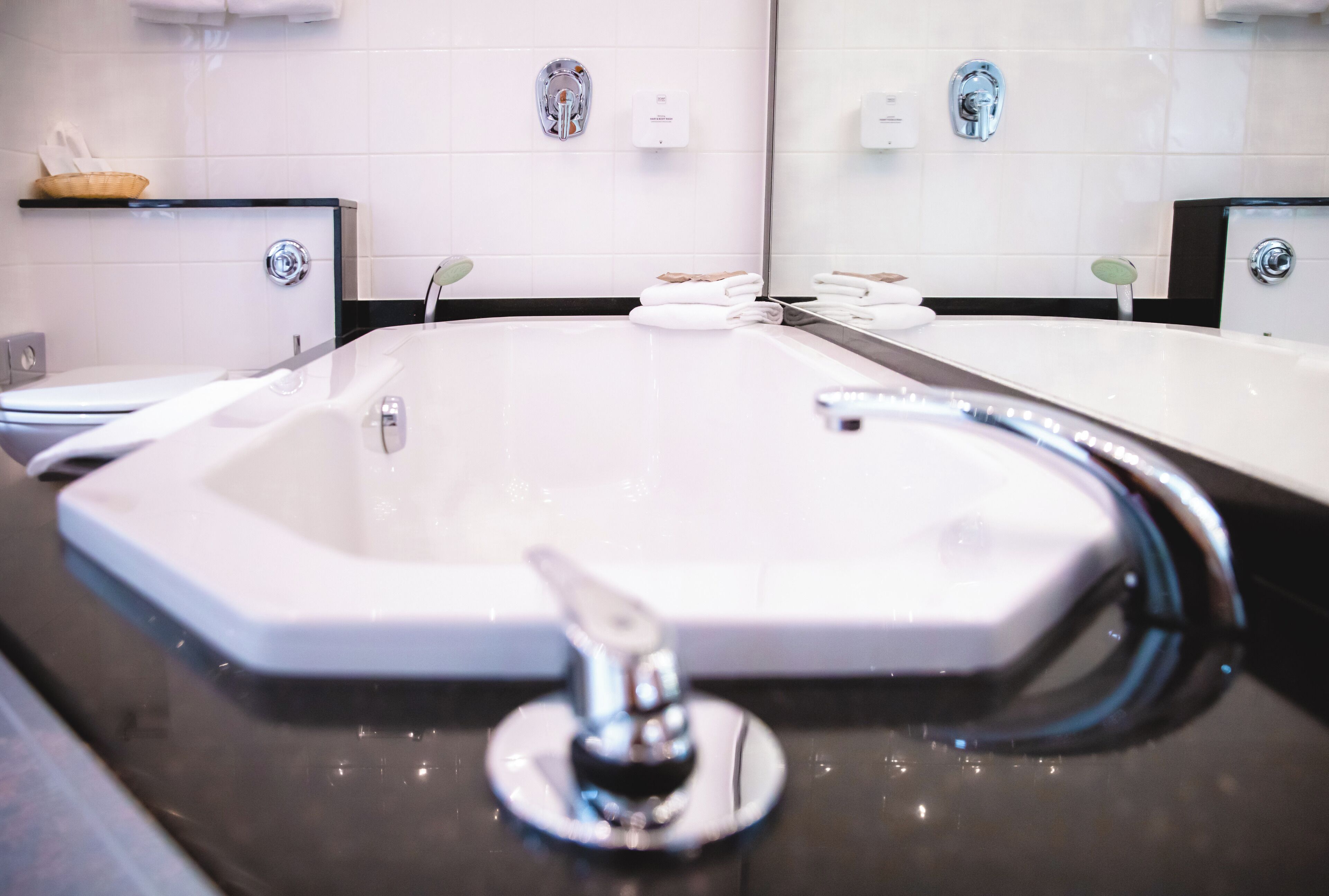 Ein modernes Badezimmer mit einem großen Waschbecken, zwei Wasserhähnen und einem Spiegel.