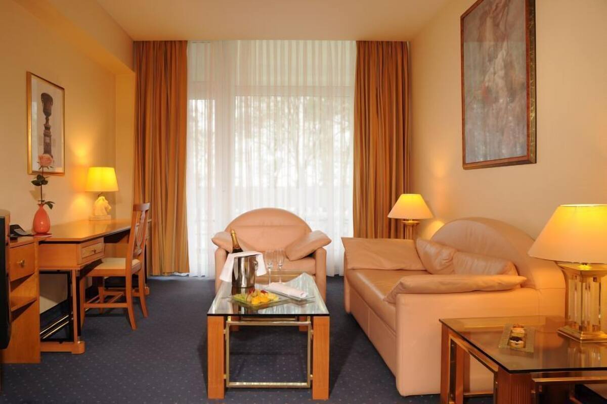 A hotel room with a sofa, a chair, a desk, and a coffee table.