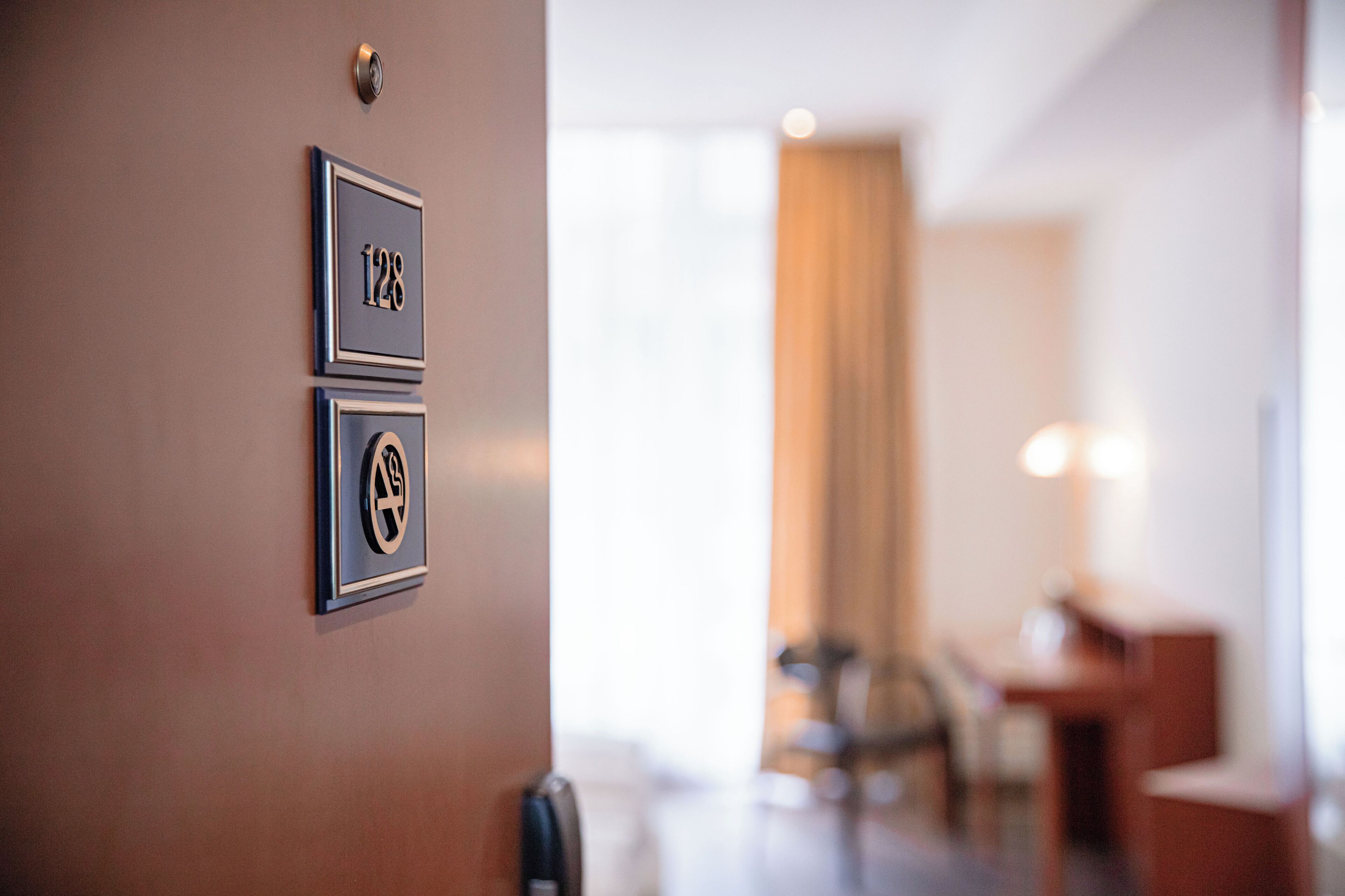 A hotel entrance with a door handle and two numbered plaques on the wall.