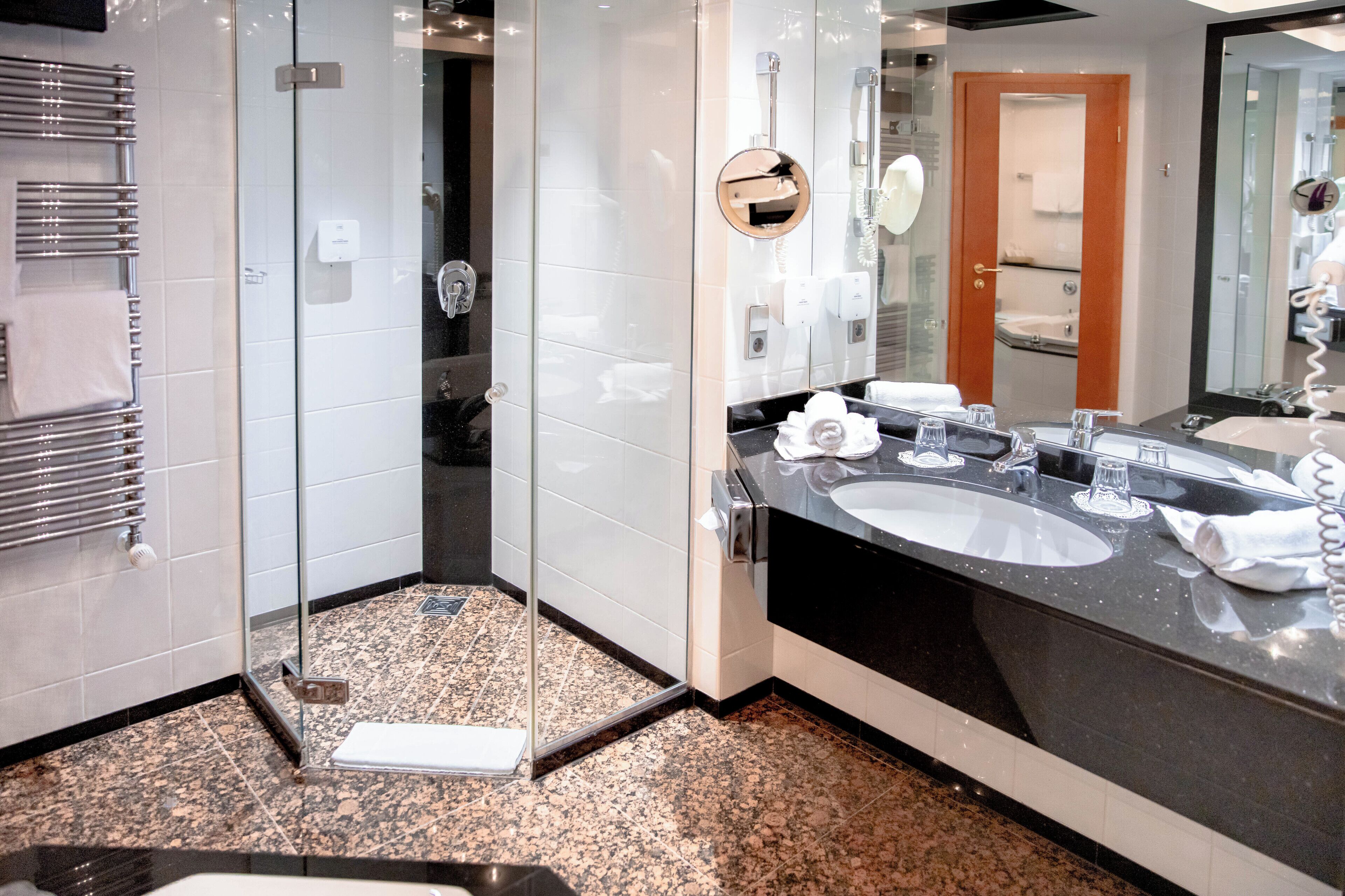 Een moderne badkamer met een douchecabine van glas, twee wasbakken en een grote spiegel.