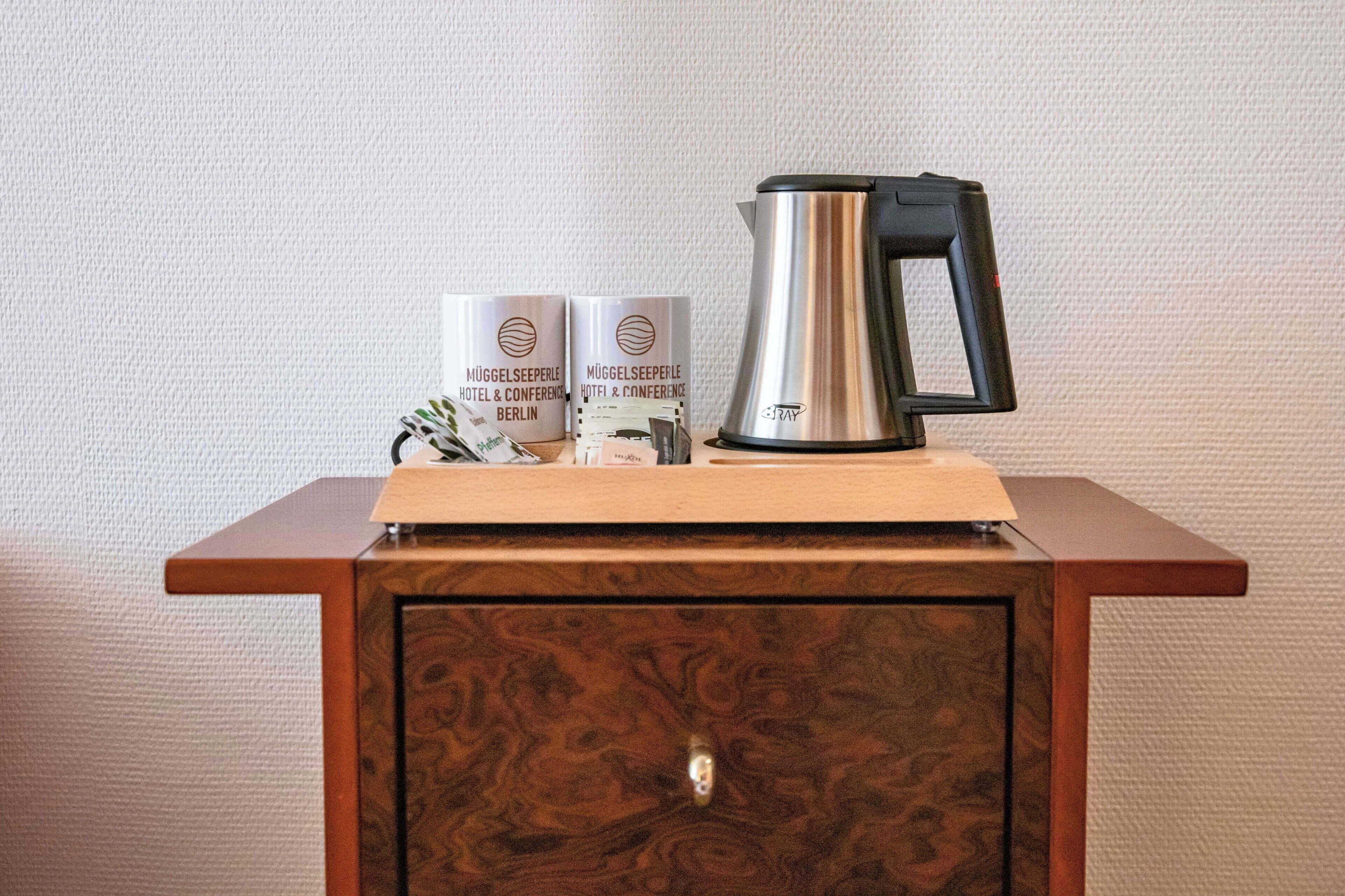 A wooden cabinet with a metallic kettle and two branded boxes on top.