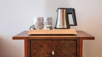 A wooden cabinet with a metallic kettle and two branded boxes on top.