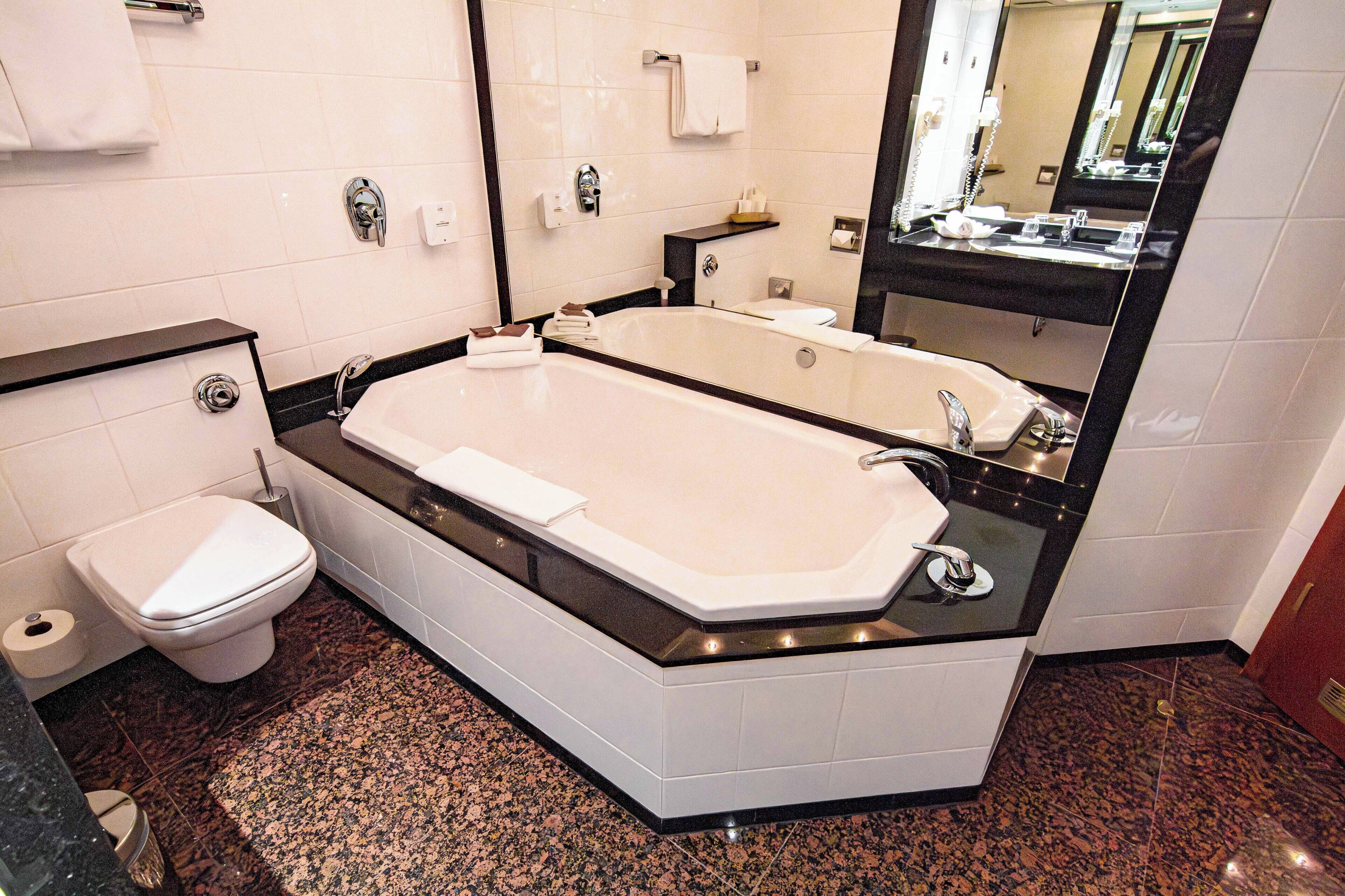 A modern bathroom with a large bathtub, a toilet, and a sink.