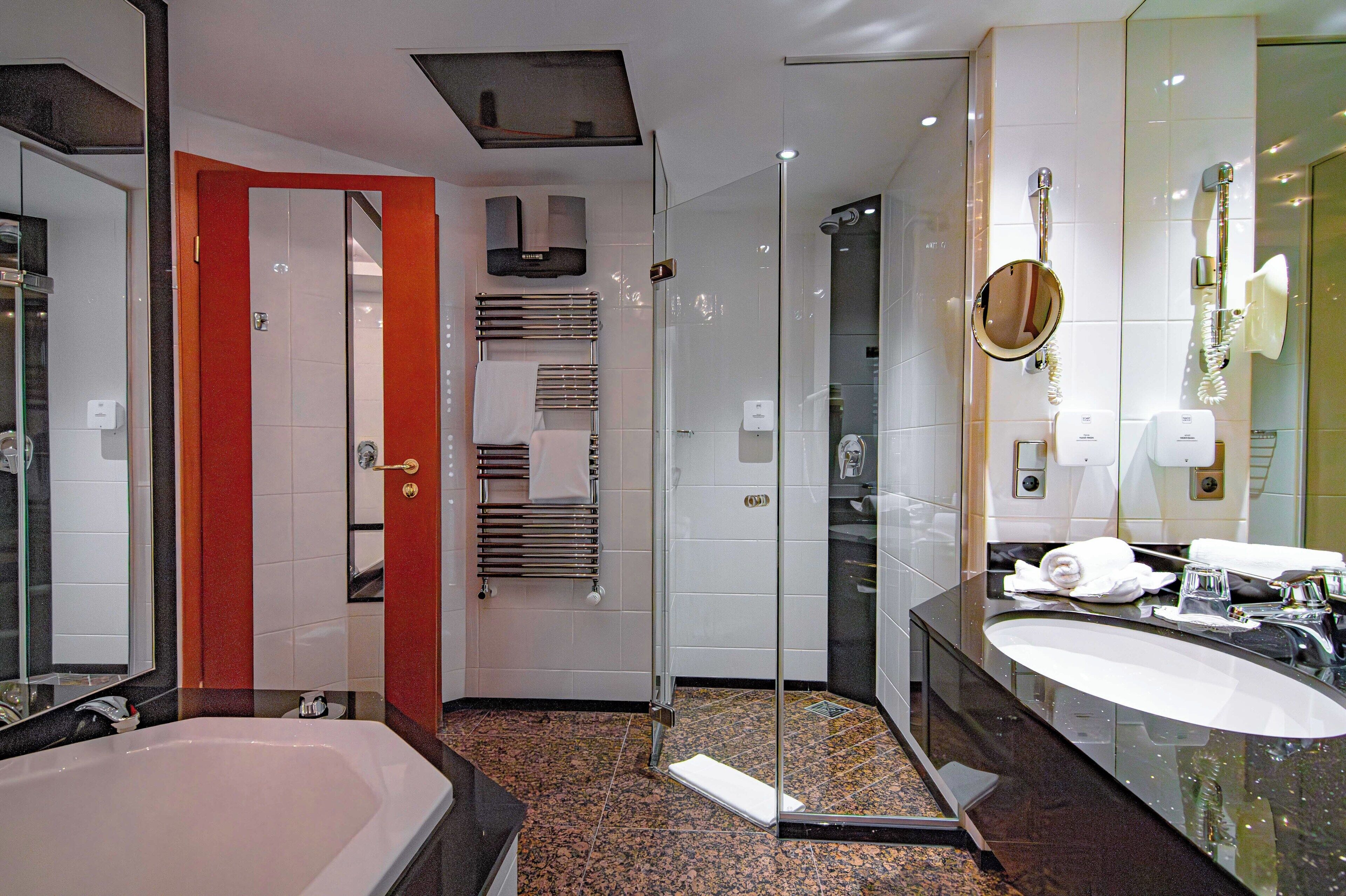 A modern bathroom with a large bathtub, a glass-enclosed shower, a vanity with a sink, and a mirror.