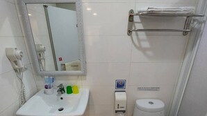 A bathroom with a sink, mirror, toilet, and hand dryer. - Funny Ximen Hotel (Taipei)