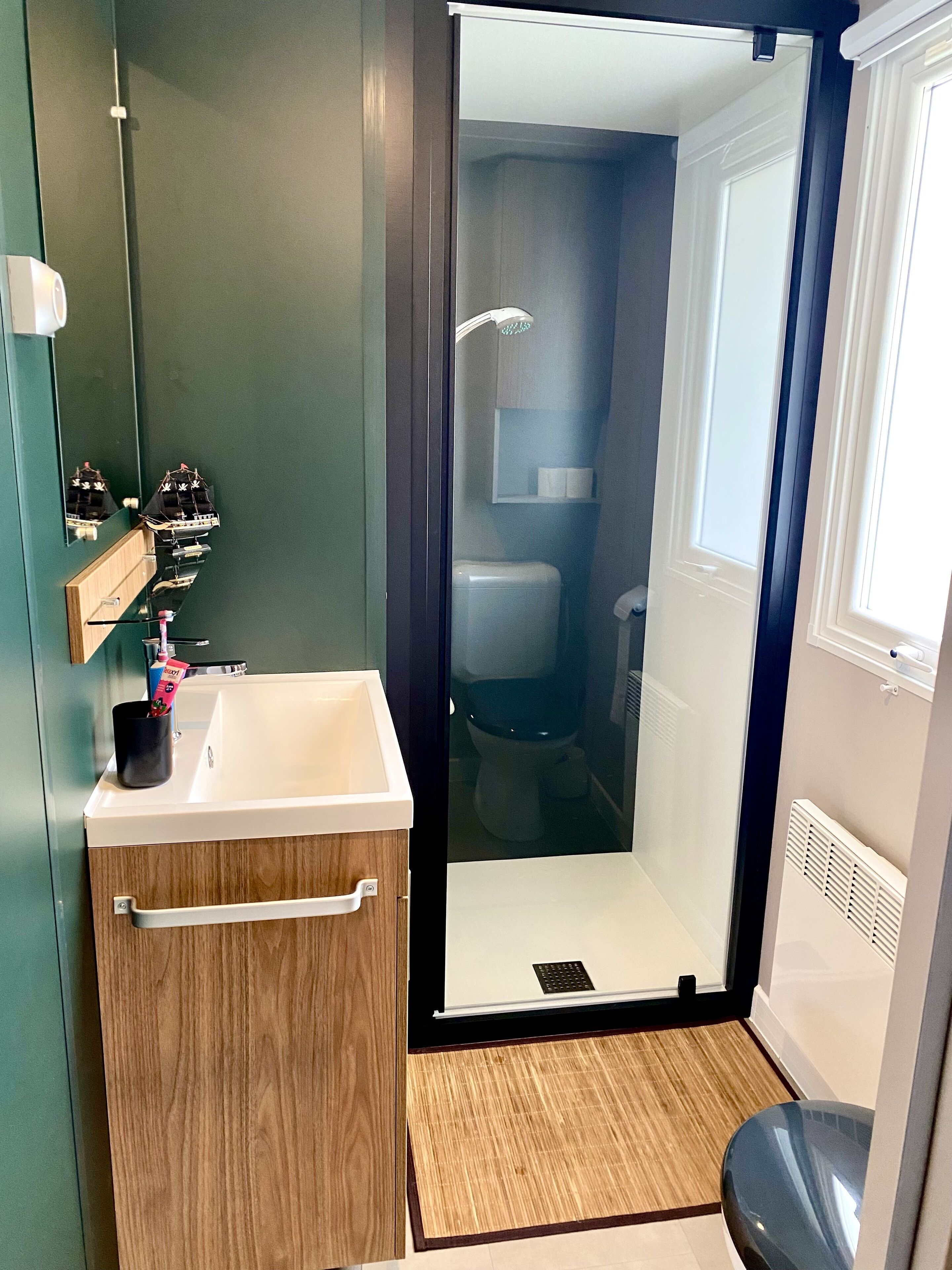 A modern bathroom with a wooden vanity, a glass shower enclosure, and a toilet.