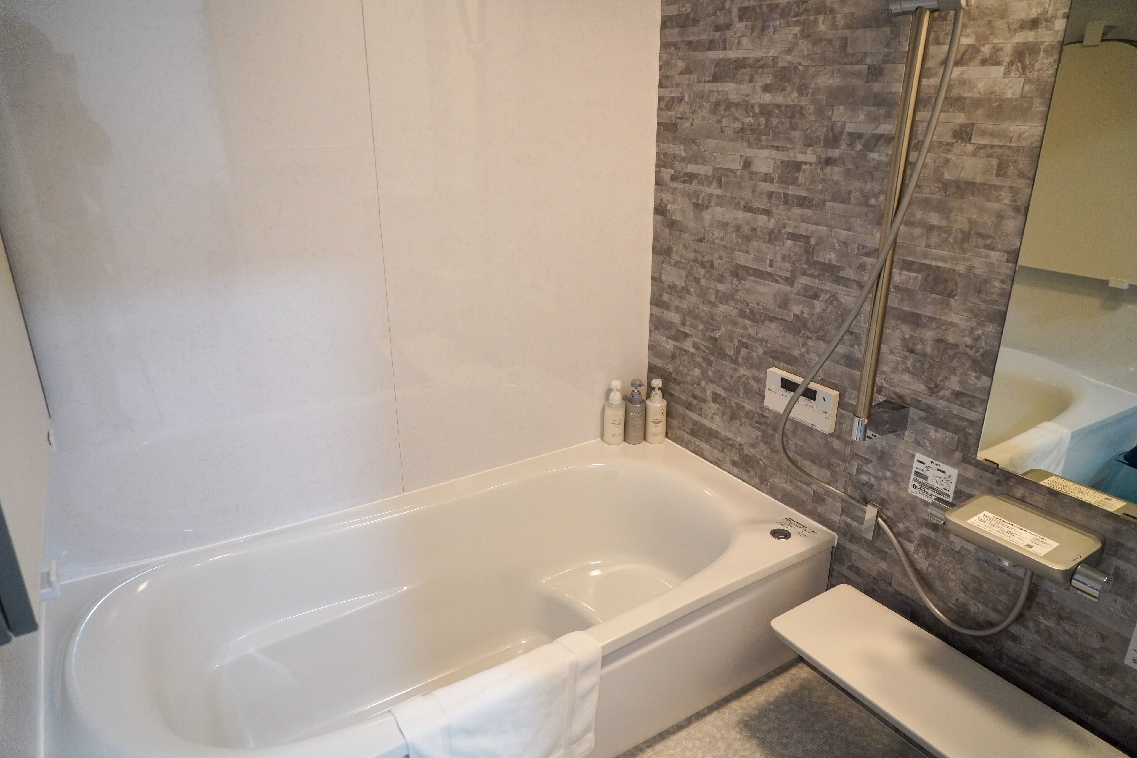 Een moderne badkamer met een bad, een douche en een wastafel met spiegel.