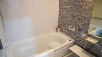 Een moderne badkamer met een bad, een douche en een wastafel met spiegel.