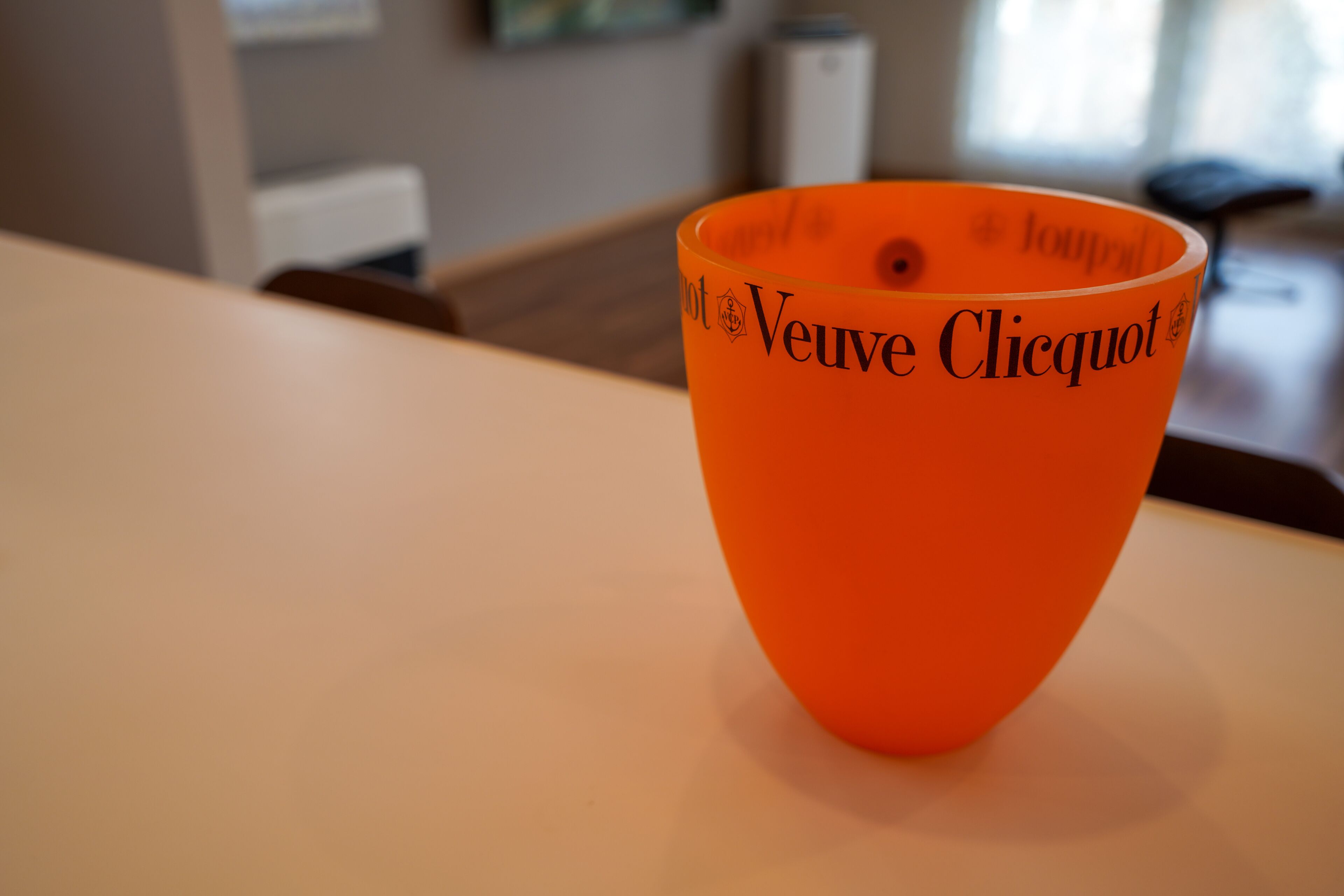 An orange bowl with the text "Veuve Clicquot" on a table.