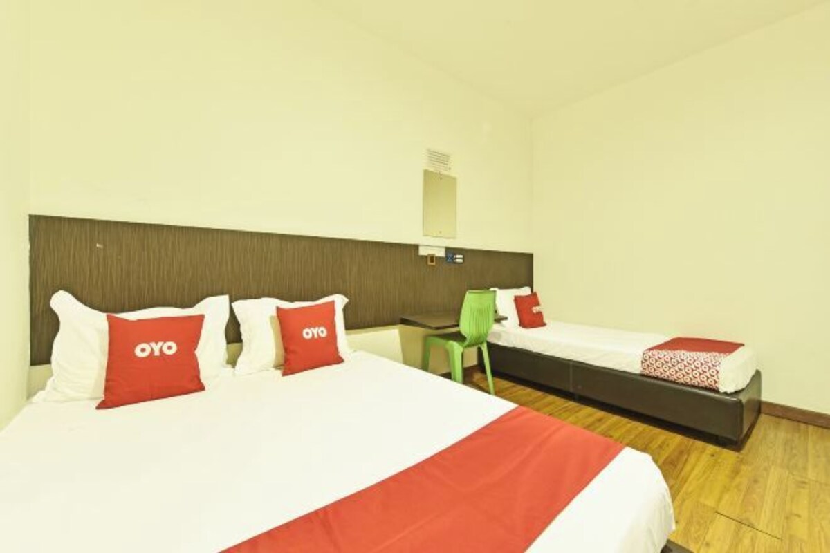 A hotel room with two beds, each with red and white bedding and pillows marked with "OYO".