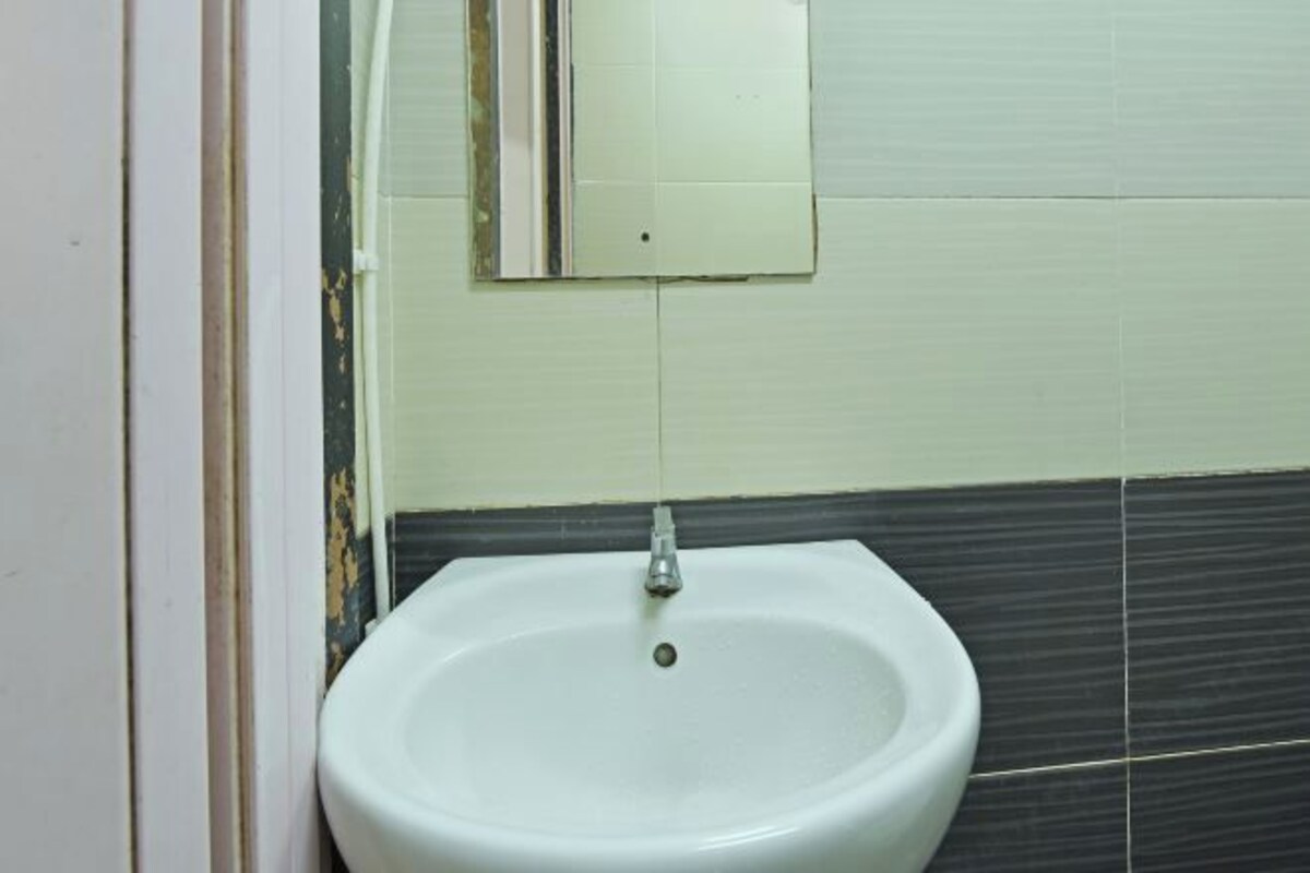 A bathroom with a white sink, a mirror, and dark tiled walls.