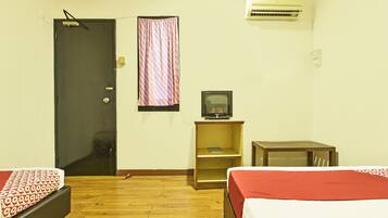 A hotel room with two beds, a television, an air conditioner, and a door.